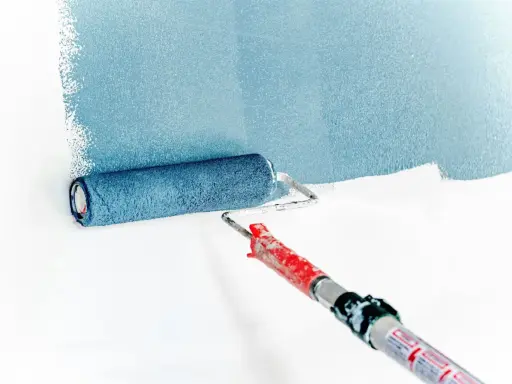 Rodillo aplicando pintura azul sobre pared blanca. La imprimación es el primer paso para un acabado perfecto.