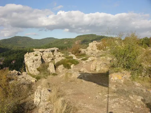 Paisaje rocoso con vegetación y colinas boscosas al fondo. Un lugar ideal que ver en Prades para disfrutar de la naturaleza.