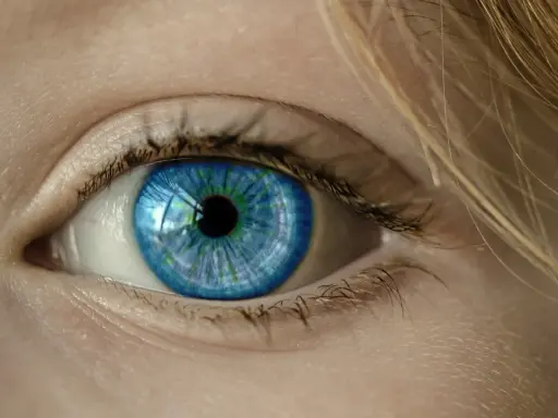 Niebieskie oko, jakby po chwilowej utracie wzroku, z refleksami zieleni i blond włosami.