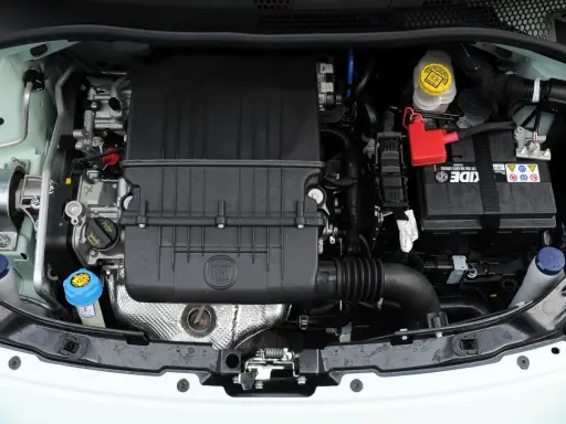 Silnik Fiata 500 L z widocznym logo FIAT na czarnej obudowie. Widać akumulator, płyny i elementy układu chłodzenia.