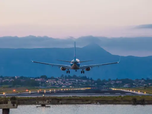 Ett flygplan landar vid Korfu flygplats i skymningen. Landningsbanans ljus lyser upp vägen.