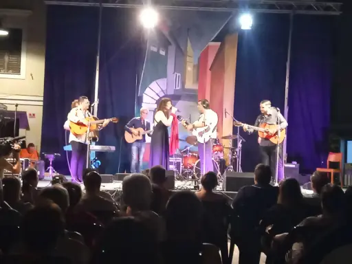 Concerto dal vivo con chitarre acustiche e voce, gli accordi di Bamboléo risuonano nell'aria.