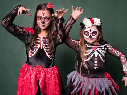 Dwie dziewczynki w strojach szkieletów z makijażem na Dzień Zmarłych. Inspiracja, jak się przebrać na Halloween.