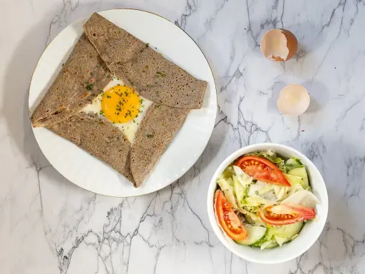 Une délicieuse crêpe complète bretonne avec un œuf coulant, accompagnée d'une salade fraîche.