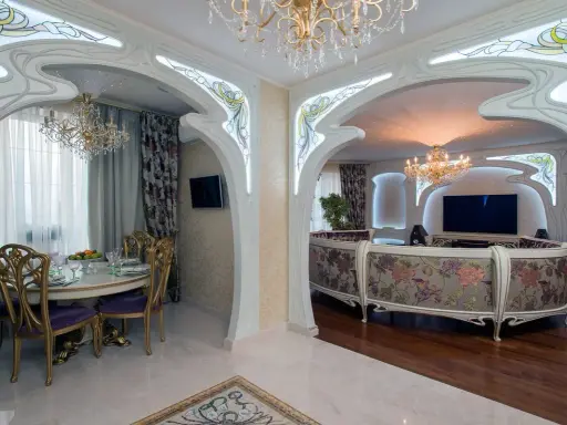 Ett lyxigt vardagsrum och matsal i art nouveau jugendstil med blommig soffa, kristallkronor och utsmyckade valv.
