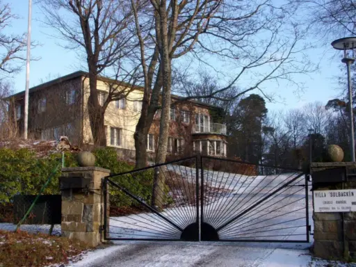 Här bor prins Carl Philip. Villa Solbacken, en vacker byggnad med en imponerande grind, omgiven av träd och snö.