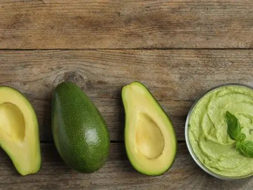Avocado lagern: Ganze und halbe Avocados, Guacamole in einer Schüssel und Avocado-Toast auf Holzuntergrund.
