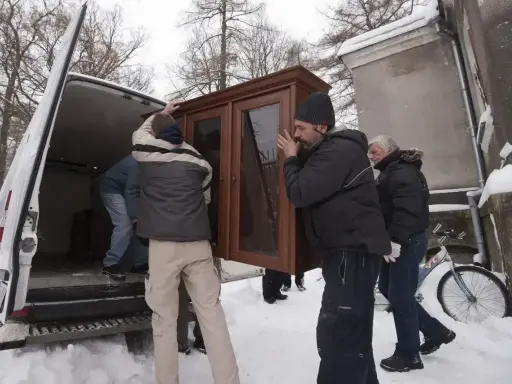 Mężczyźni wynoszą mebel z domu, by uniknąć eksmisji. Zimowa aura i śnieg nie powstrzymują przeprowadzki.