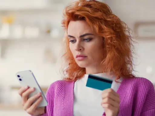 Zastanawia się, co to jest dip, przeglądając ofertę w telefonie z kartą w dłoni.