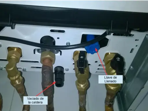 Detalle de conexiones de caldera. Flecha roja señala "Vaciado de la caldera" y otra flecha roja indica "Llave de Llenado".