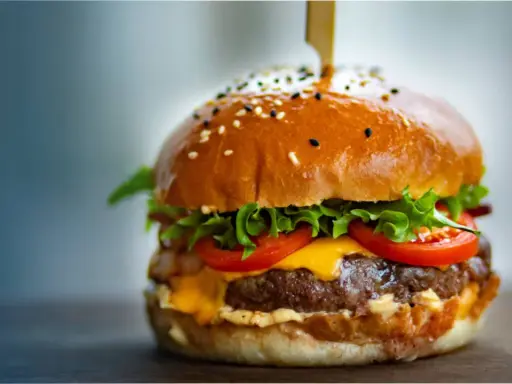 Un délicieux burger, avec sa brioche dorée, sa viande juteuse, son fromage fondant, sa laitue croquante et ses tomates fraîches. On se demande d'où vient le burger, ce classique indémodable.