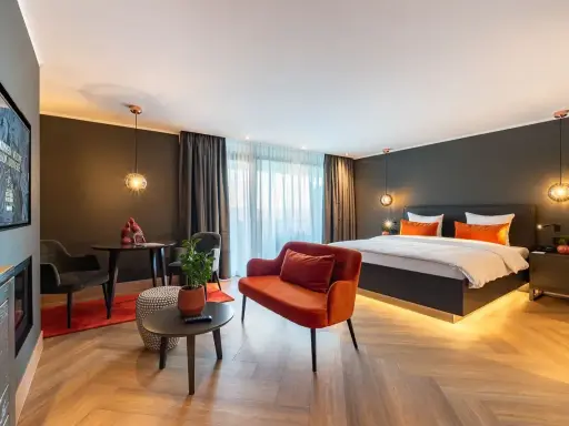 Modern Hotelzimmer mit großem Bett, orangefarbenem Sofa und Sitzbereich.