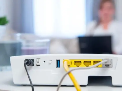 Router vom Strom trennen wie lange? Das Bild zeigt die Rückseite eines weißen Routers mit Netzteilanschluss, Schalter und LAN-Ports.