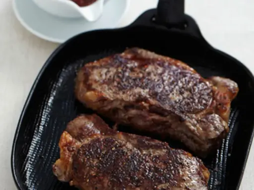 Zwei saftige Rumpsteaks braten in einer Grillpfanne, perfekt gewürzt und bereit zum Genuss.