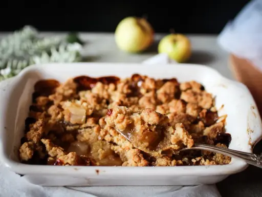 Une cuillère prélève une portion généreuse de ce vrai recette crumble aux pommes caramélisées, fondant et croustillant.