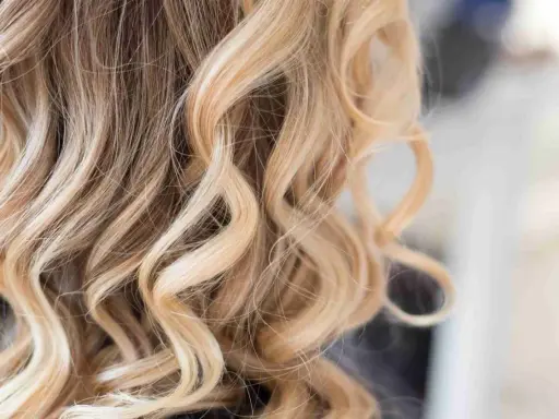 Piękne, falowane włosy z subtelnym balejażem blond, dodającym im blasku i głębi.
