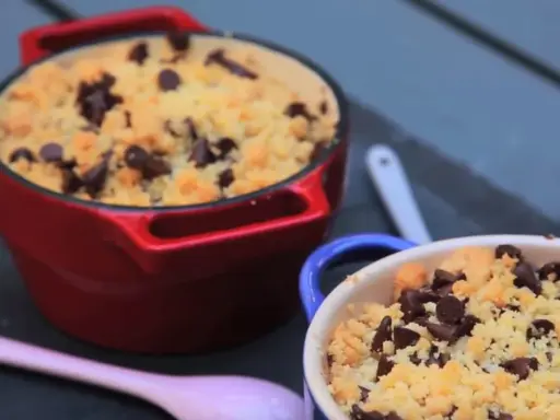 Deux ramequins de crumble pomme banane chocolat, l'un rouge, l'autre bleu, garnis de pépites de chocolat.