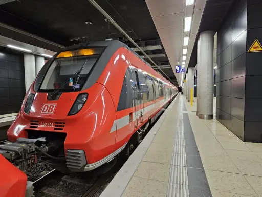 Röd DB-tåg på en station, redo att ta dig från berlin flygplats till centrum.