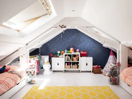 Kreative kinderzimmer dachboden ideen: zwei Betten, Spielzeug, Kleiderständer und ein Sternenhimmel an der Wand schaffen eine gemütliche Atmosphäre.