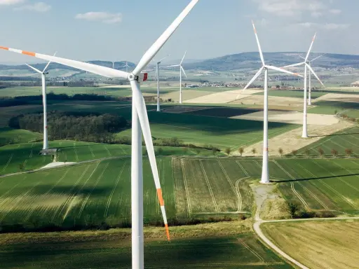 Weite Felder mit vielen weißen onshore Windkraftanlagen unter blauem Himmel.