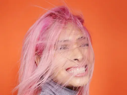 Frauenkopf mit pinken Haaren, die im Wind wehen. Ein Antistatik-Spray für Haare hätte hier Wunder gewirkt.