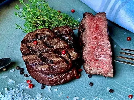 Perfekt gegrilltes Rinderfilet mit zarten rosa Kern, garniert mit Thymian, Pfeffer und grobem Salz. Ein Genuss für Fleischliebhaber!