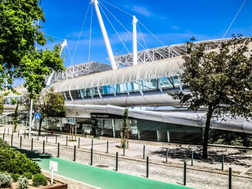 Moderne Architektur auf dem Expo Gelände Lissabon mit einem langen, geschwungenen Dach und Glasfassaden.