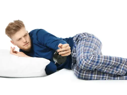 Mann liegt auf der Seite, weckt den Wecker. Die beste Schlafposition bei COPD kann helfen, besser zu atmen.