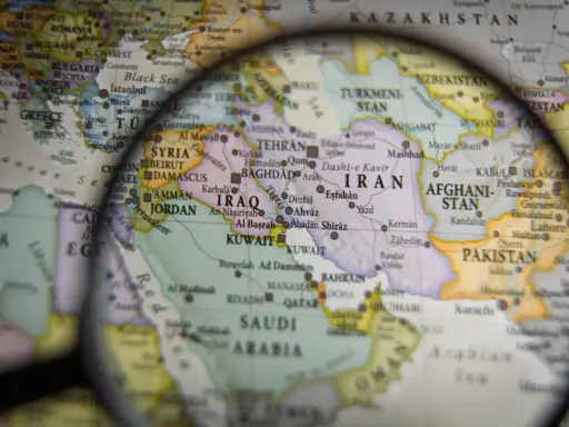 Mapa świata pod lupą, widoczne kraje Bliskiego Wschodu i Azji Południowej. W centrum Iran, Irak, Arabia Saudyjska.