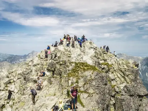 Rysy jak się przygotować: tłum turystów na szczycie, skaliste zbocza, widok na Tatry. Warto zabrać wodę i mapę.