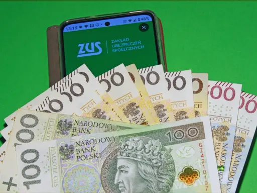 Złotówki i ekran telefonu z logo ZUS. Ile trzeba pracować za granicą żeby dostać emeryturę?