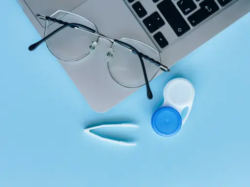 Okulary, pojemnik na soczewki i pęseta leżą obok laptopa. Czy można nosić soczewki i okulary jednocześnie?