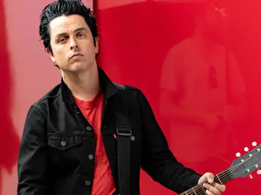 Billie Joe Armstrong, green day sångare, med sin Gibson Les Paul gitarr mot en röd bakgrund.