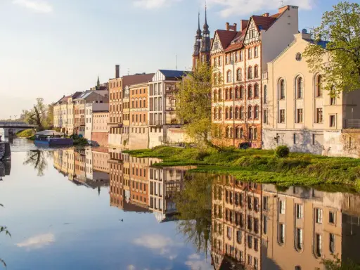 Nad rzeką w Opolu, w blasku słońca, odbijają się kamienice. To jedne z wielu magicznych miejsc opolskich, które zachwycają spokojem i pięknem.
