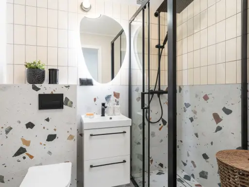 Nowoczesna łazienka z prysznicem i umywalką. Inspiracja, jak odświeżyć łazienkę, z terazzo i czarnymi detalami.