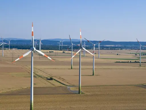 Großer onshore windpark in einer weiten Feldlandschaft unter blauem Himmel.