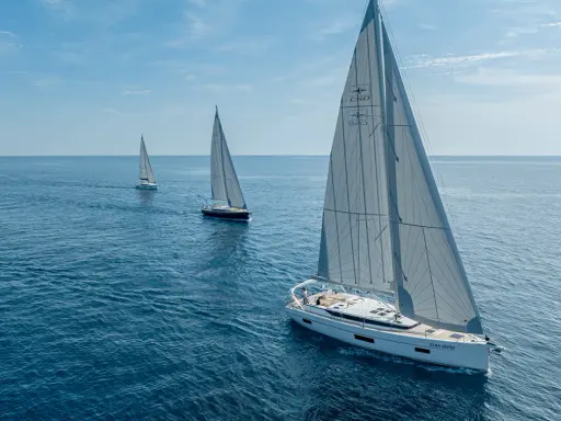 Drei weiße Segelboote segeln auf dem blauen Meer. Die Kosten für ein Segelboot wie dieses sind hoch, aber das Erlebnis unbezahlbar.