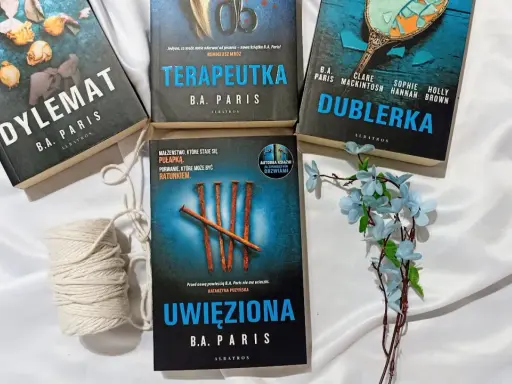 Książki B.A. Paris: "Dylemat", "Terapeutka", "Dublerka" i "Uwięziona" ułożone na białym tle.