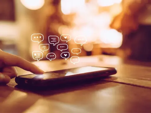 Palec dotyka ekranu telefonu, a nad nim pojawiają się dymki czatu. Dowiedz się, jak odzyskać wiadomości z kosza w telefonie.