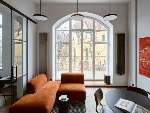 Nowoczesny salon z pomarańczową kanapą, czarnym stolikiem i obrazem. Jakie dodatki podkreślają styl?