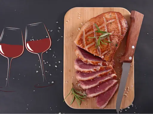 Quel vin avec magret de canard ? Deux verres de vin rouge et un magret de canard tranché sur une planche en bois, prêts à être dégustés.