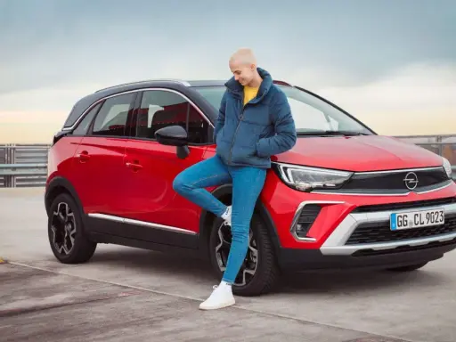 Joven apoyada en un Opel Crossland X rojo. Evita problemas con la correa de distribución de tu Opel Crossland X con un mantenimiento adecuado.