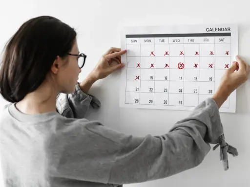 Mujer revisa calendario, marcando días. No me baja la regla y no estoy embarazada, preocupación en su rostro.