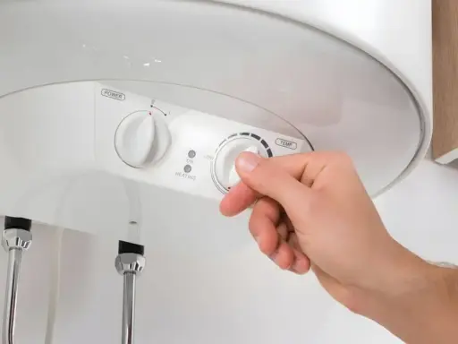 Mano ajustando el termostato de un termo eléctrico. Averigua cuanto dura un termo eléctrico y optimiza su uso.