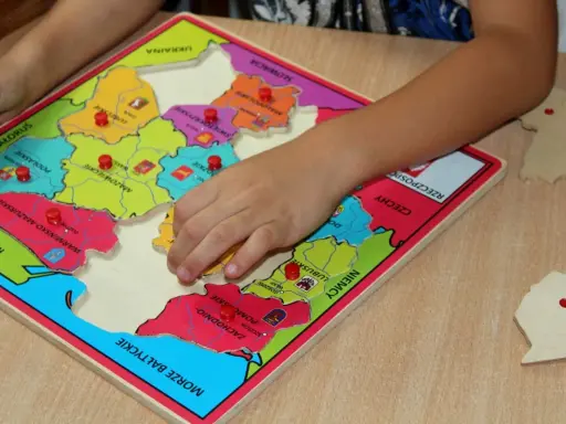 Dziecko układa puzzle z mapą Polski, ucząc się regionów. To świetne gry dydaktyczne w przedszkolu.