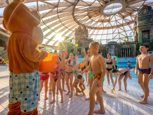 Maskotka rzuca piłeczki dzieciom w aquaparku w Budapeszcie. Radosna zabawa pod szklaną kopułą.