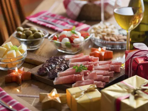 Eleganckie menu na sylwestra w domu: wędliny, sery, oliwki, pomidorki z mozzarellą, orzechy, wino i prezenty.