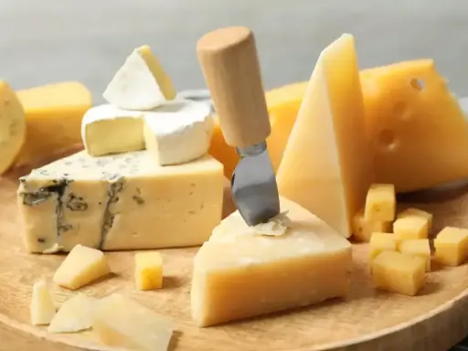 Deska serów: pleśniowy, camembert i twarde sery, w tym ser sałatkowy pokrojony w kostkę.