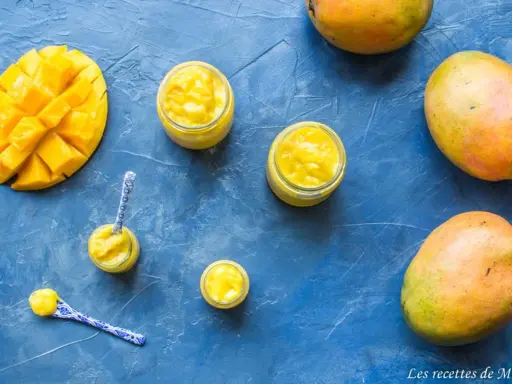 Délicieux curd mangue dans des petits pots, avec des mangues fraîches et des cuillères décorées. Un délice tropical !