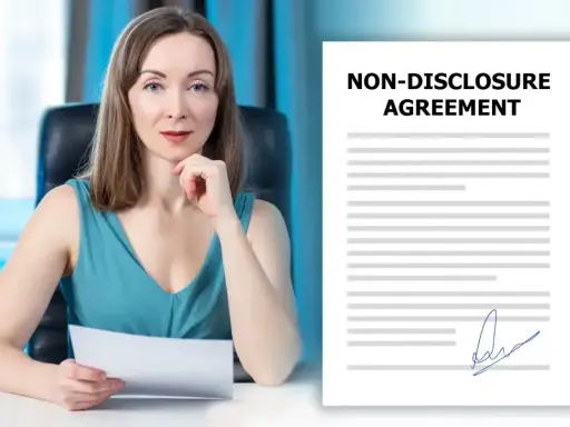 Kobieta w biurze trzyma dokument NDA. Obok niej leży podpisana umowa o poufności.